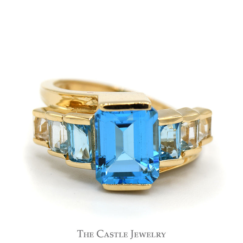 Emerald Cut Blue Topaz Ring with Graduated Design in 14k Yellow Gold Bypass Setting