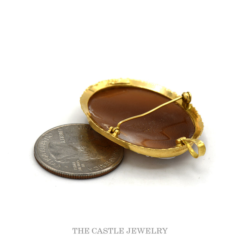 Back view of the 18k yellow gold shell cameo showing pin clasp, with quarter for scale